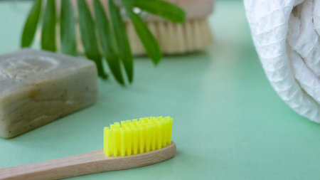 Eco natural bamboo toothbrush on green background with toiletries, natural soap, body brush and...