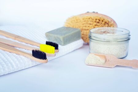 Eco natural bamboo toothbrush on white background with toiletries, natural soap, scrub, body brush and waffle towel. Zero waste concept. Choice plastic free items. Selective focusの写真素材