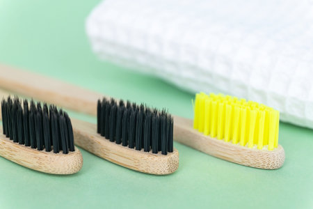 Eco natural bamboo toothbrushes on green background with waffle towel. Zero waste concept. Choice...