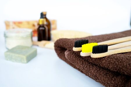 Eco natural bamboo toothbrush on white background with toiletries, natural soap, scrub, body brush and soft broun towel. Zero waste concept. Choice plastic free items. Selective focus.の写真素材
