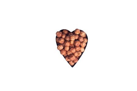 Healthy eating, dieting, vegetarian food concept. Close up of peeled hazelnut in heart shape form on white background.の写真素材