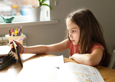 Caucasian preteen girl concentrated on her task with tablet. Concept of distance learning in...