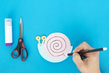 Step by step children's cardboard crafts - colored swinging snail. Scissors, glue, paper sheets. Set for kids art. Children activity in kindergarten, school, at home. Step 7.の写真素材