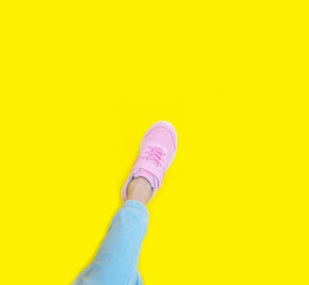 pink sneakers and blue jeans on a yellow background. Mockup. Copy spaceの写真素材