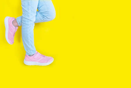 pink sneakers and blue jeans on a yellow background. Mockup. Copy spaceの写真素材