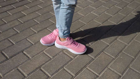 Girl in pink sneakers on cobblestone street. kids teenagers shoesの写真素材