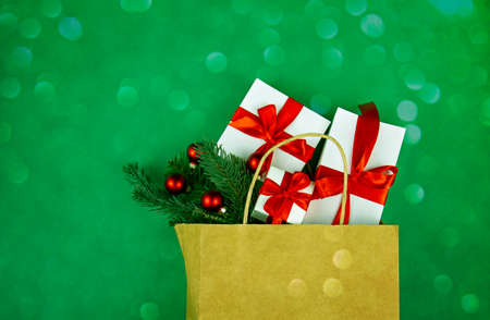 Kraft paper bag on green background. With gift boxes, spruce branches and christmas decoration. Black friday christmas gift preparation concept.の写真素材