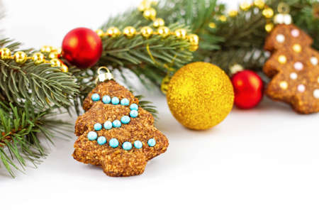 Homemade gingerbread in shape of Christmas tree decorated with sugar balls with Christmas branch on background with gold and red balls. Copy space. Bannerの写真素材