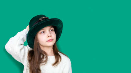 Portrait of pretty pensive emotional caucasian girl in fancy green leprechaun hat with gold buckle. concept promotion mockup. St. Patricks Day. Banner. Copy spaceの写真素材