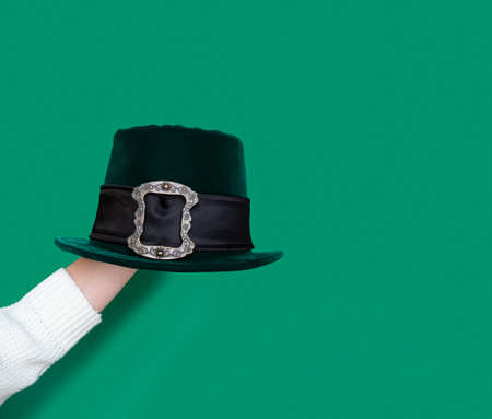 Green leprechaun hat with gold buckle on arm on green background. concept of St Patricks Day. mockup. Copy textの写真素材