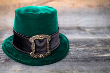 Green leprechaun hat with gold buckle on rough wood background. concept of St Patricks Day. mockup. Copy textの写真素材