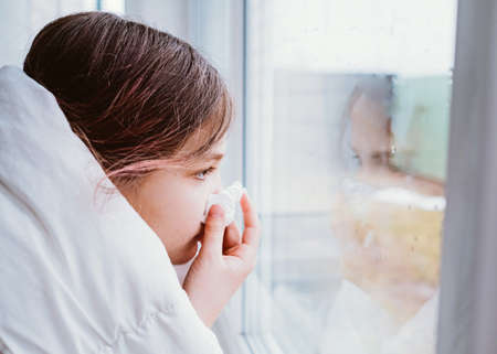 A cold girl blows her nose in a white rag on white background. Rhinitis snot runny nose stuffy nose. Allergy Preteen girl with handkerchief. medical conceptの写真素材