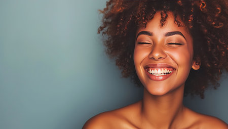 Happy dark-skinned woman with a wide smile on a blue background. The concept of positivity and beauty.の素材