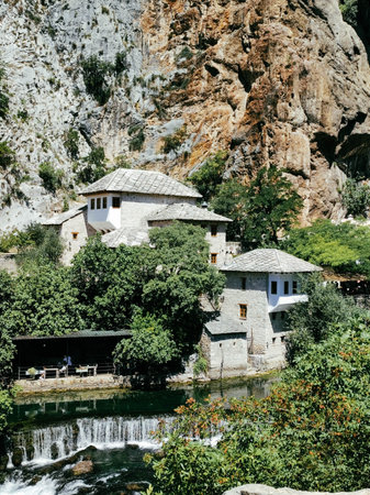Blagaj Tekke monastery built into rocky canyon above a river waterfall. Iconic Bosnia and Herzegovina landmark with historic Islamic architecture. Vintage color tones and subtle film grainの写真素材