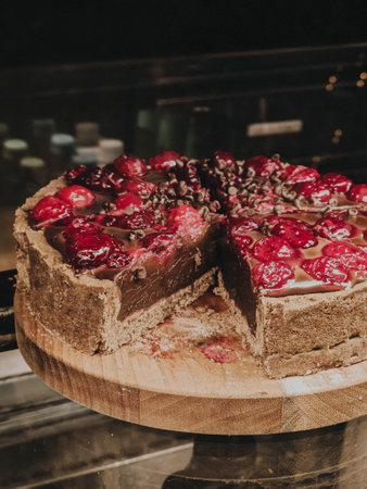 Chocolate cherry cake on wooden stand with glossy topping and berries, styled with vintage color...