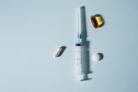 Tablets and an empty syringe on white