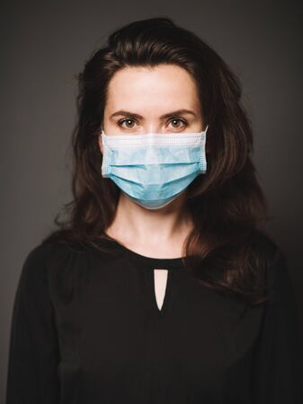 Portrait of an woman in a medical mask. The background is dark.の写真素材