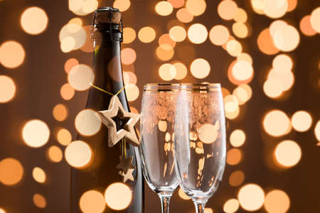 Festive Champagne bottle and two glasses. Fragment. Golden color and garlands.の写真素材