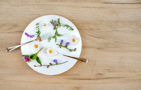 Spring flowers on plate. Wooden background. Top view. Flat lay. Copy space. Summer and spring conceptの写真素材