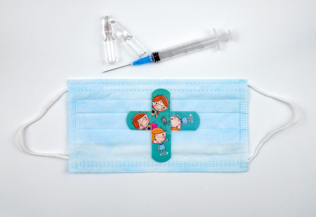 Medical kids adhesive in shape of cross on blue mask, syringe, ampules on white background....
