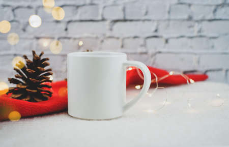 Santa hat and mug of coffee on white bricks background with lights bokeh. Christmas picture.の写真素材
