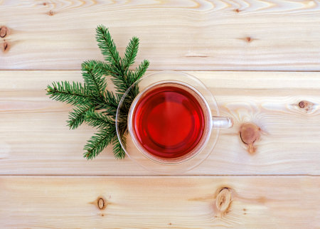 Glass tea cup and pine branches on wooden background, top view, creativity minimalismの写真素材