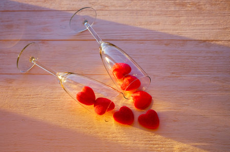 Two glasses of champange and marmalade red hearts on wooden table with sunlight effect. Romantic creative background with copy space. Selective focusの写真素材