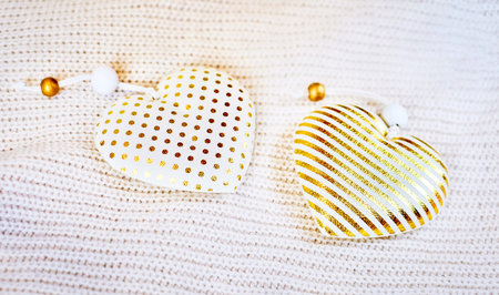 Two Christmas toys golden hearts on knitted backgroud, pastel colors. Holiday background, vintage...