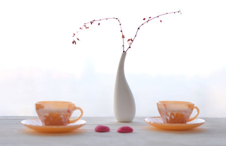 Background decorative vase with branches and two tea cups on sky background, selective focusの写真素材