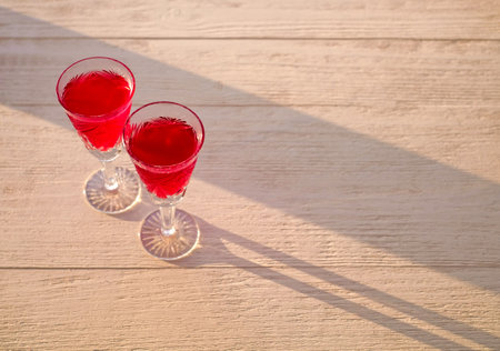 Two wine glasses on the wooden table in a sunny day. Love, romance, holiday, celebration concept. Copy space.の素材 [FY310164182291]