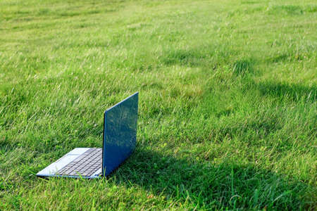 Laptop on natural green grass background. Freelance concept, work and study outside. Copy spaceの写真素材