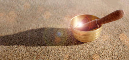 Himalayan tibetian singing bowl on sand with sunlight, bokeh. Harmony and relaxation concept. Copy space.の写真素材