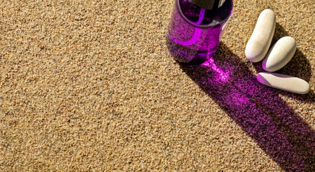 Purple bottle with suntan spray and stones on sand, sun care protection, copy spaceの写真素材