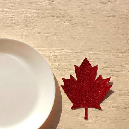 Plate and maple leaf made of paper in the style of Canada on wooden table, sunlight, copy space. Square imageの写真素材