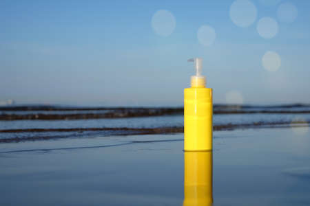 Sunbath lotion sun protection in yellow plastic bottle on sea background with bokeh, copy space.の写真素材