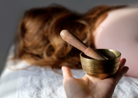 Singing bowl in hand at spa salon with woman at background. Sound therapy, healthy lifestyle, body...