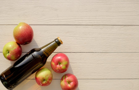 Bottle of cider and red apples on wooden background, top view, copy spaceの写真素材