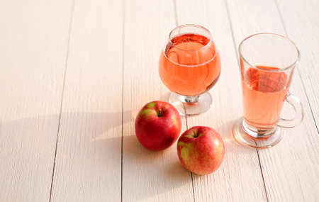 Glasses of carbonated sweet water or cider and red apples on wooden background, copy spaceの写真素材