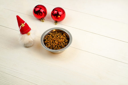 Food for pets in bowl on wooden background, toy and red christmas balls, copy spaceの写真素材