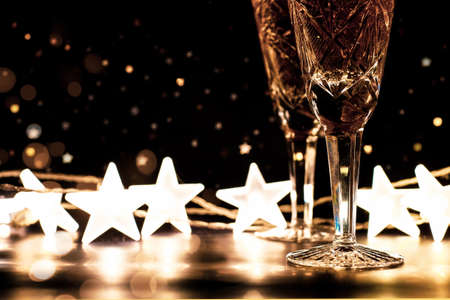 Two glasses of champagne on dark New Year background with lights, bokeh and stars with copy spaceの写真素材