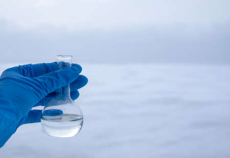 Hand in glove holding water sample from the frozen sea, water diversion, ecology concept. Copy spaceの写真素材