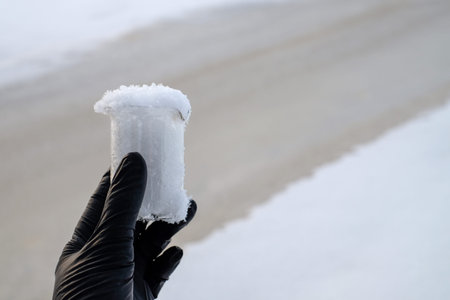 Hand in black glove holding snow sample, water diversion, ecology concept. Copy space