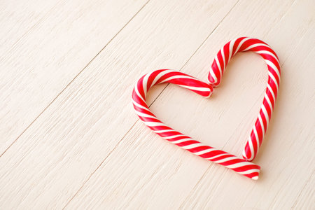 Christmas candy canes shaped like heart on wooden backgroundの写真素材