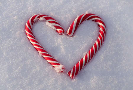 Christmas candy canes as heart on snow backround close-upの写真素材
