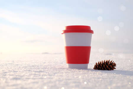 Thermo mug and pine cone on snow background, winter nature with sunlightの写真素材