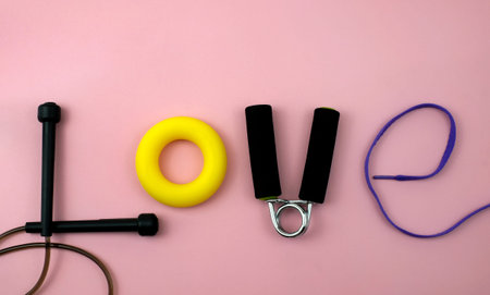 Word love made from the sport accessories on a pink background. Love for fitness