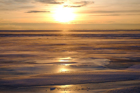 Golden light at sunset and frozen sea. Cold windy and frosty weather. Winter landscape,...