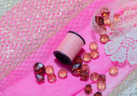 pink thread, paper for needlework, on a pink background, beads for needlework