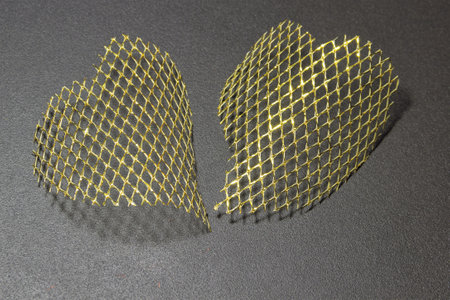 two hearts made of gold mesh on a black matte backgroundの写真素材