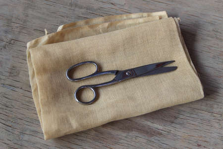 scissors on a piece of natural-colored linen cloth on a wooden countertopの写真素材